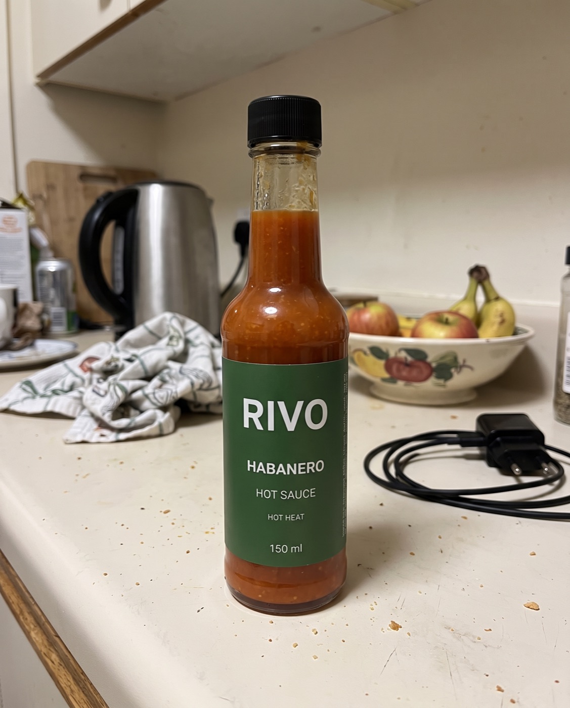 Before: an amateur phone photo of a hot sauce bottle on a messy kitchen counter